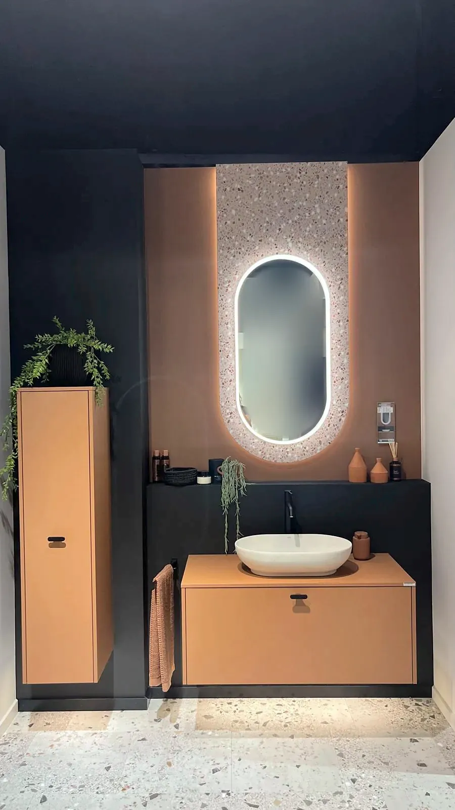 Badmöbel in Terracotta mit Aufsatzbecken und beleuchtetem Spiegel in einer Ausstellung
