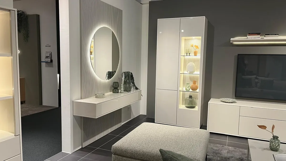 Wohnwand in Weiß mit Vitrine, Lowboard und beleuchtetem Spiegel in einer Ausstellung