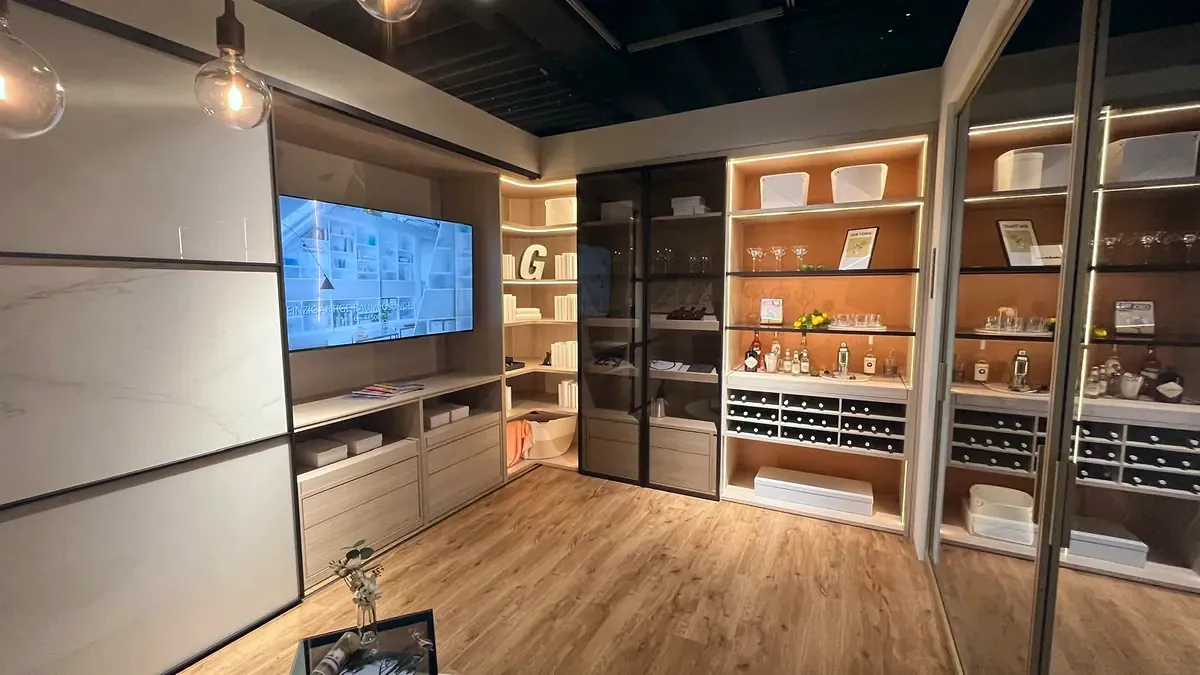 Wohnwand mit Regalen, Glasvitrinen und Fernseher in einer Ausstellung